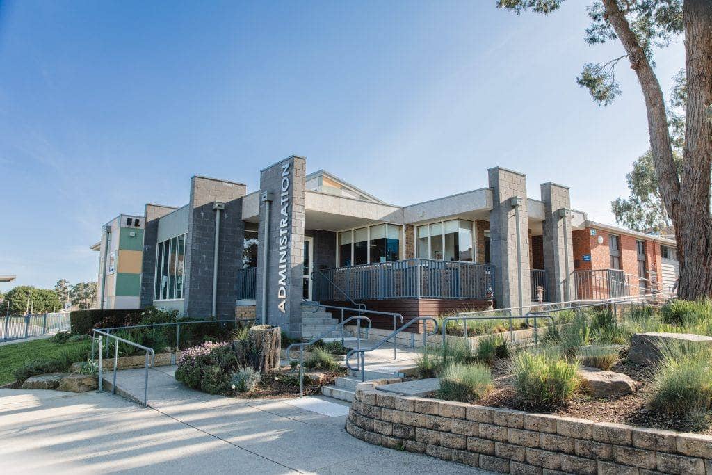 The administration building at Maranatha Christian School, a modern grey-brick building fronted by landscaped native garden beds.